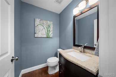 Half bathroom featuring vanity and wood floors