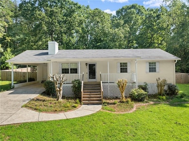 View of front of home with covered porch, driveway, a carport, and a chimney