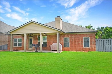 Rear view of house with a ceiling fan, a chimney, a patio area, and brick siding