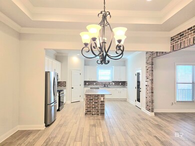 Kitchen featuring crown molding, pendant lighting, white cabinets, freestanding refrigerator, and backsplash