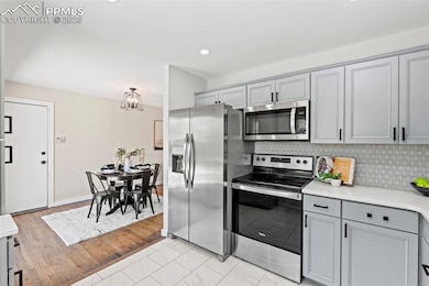 Kitchen with stainless steel appliances, gray cabinets, light countertops, decorative backsplash, and recessed lighting