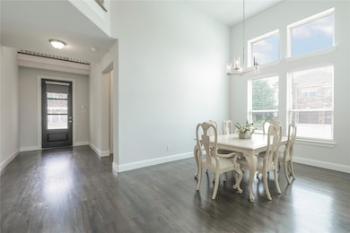 Dining area with a high ceiling, an inviting chandelier, plenty of natural light, and dark hardwood / wood-style flooring
