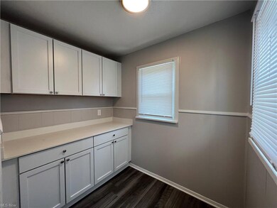 Kitchen with dark hardwood flooring, light countertops, and white cabinetry