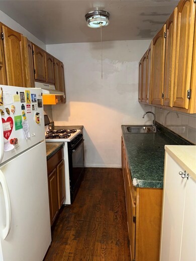 Kitchen with refrigerator, sink, dark hardwood / wood-style flooring, stove, and exhaust hood
