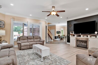 Living room with ceiling fan, light hardwood / wood-style flooring, a fireplace, and crown molding
