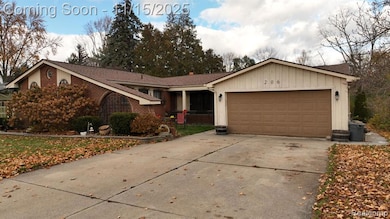 Ranch-style house featuring driveway, an attached garage, brick siding, and board and batten siding