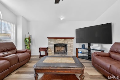 Living area featuring light wood finished floors and a stone fireplace