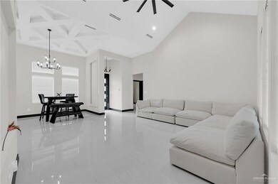 Living area featuring a chandelier, a towering ceiling, a ceiling fan, light marble finish floors, and coffered ceiling