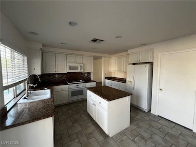 Kitchen featuring a sink, visible vents, dark coun