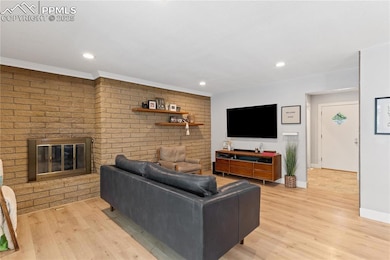 Living room with light wood-style floors, crown molding, recessed lighting, and fireplace