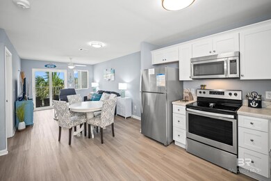 Kitchen with stainless steel appliances, white cabinets, open floor plan, light wood-style floors, and a ceiling fan