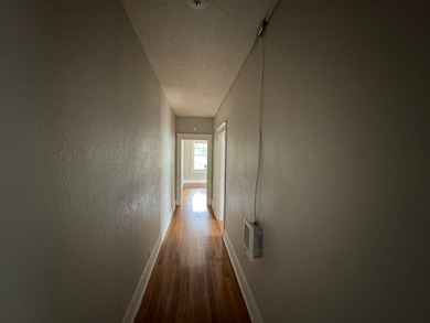 Corridor featuring a textured ceiling, dark wood finished floors, and a textured wall