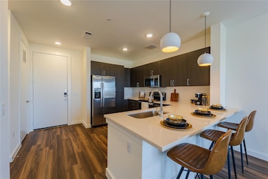 Kitchen featuring stainless steel appliances, a peninsula, visible vents, light countertops, and a breakfast bar