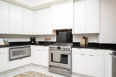 Kitchen featuring dark stone counters, custom exha