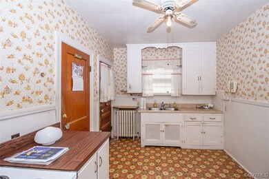 Kitchen with sink, white cabinets, butcher block countertops, radiator heating unit, and ceiling fan