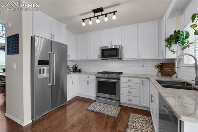 Kitchen with premium appliances, healthy amount of natural light, dark wood-style floors, and tasteful backsplash