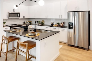 Kitchen featuring stainless steel appliances, decorative backsplash, sink, and a center island with sink