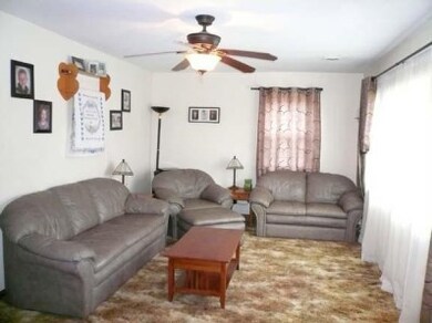 Large living room with ceiling fan.  Original hardwood under the carpet.