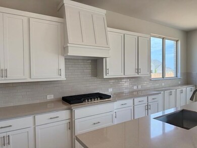 Kitchen featuring white cabinets, backsplash, pre