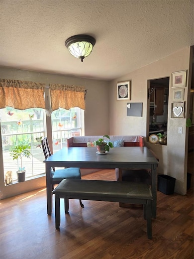 Dining space with a textured ceiling, wood finished floors, and lofted ceiling