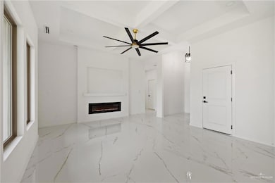 Unfurnished living room featuring a glass covered fireplace, beam ceiling, ceiling fan, a raised ceiling, and marble finish floors