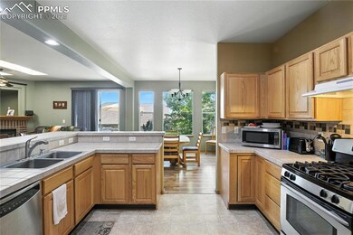 Kitchen featuring appliances with stainless steel finishes, under cabinet range hood, tile counters, and backsplash