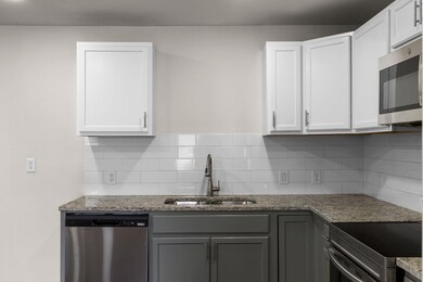 Kitchen with white cabinetry, appliances with stai