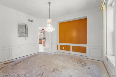 Unfurnished dining area featuring a decorative wall, ornamental molding, wainscoting, and a chandelier