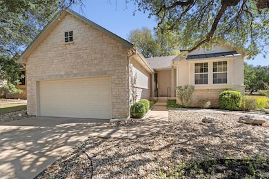 View of front of home with stone siding, driveway, and a shingled roof