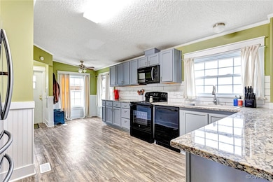 Kitchen with black appliances, gray cabinets, sink