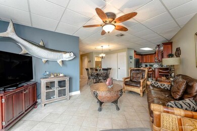 Living area featuring a ceiling fan, light tile patterned floors, a paneled ceiling, and visible vents