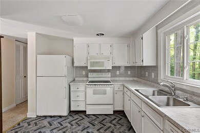 Kitchen featuring tasteful backsplash, white cabin