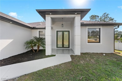 View of exterior entry featuring a lawn and french