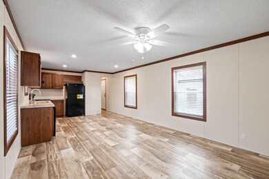Open concept living area (924 sq. ft. total) flowing into the kitchen with a ceiling fan and LED can lights throughout