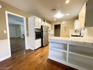 Kitchen with tile counters, white cabinets, a peni