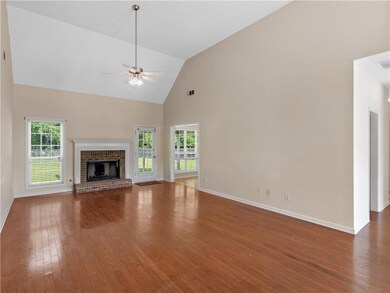 Unfurnished living room with a ceiling fan, hardwood / wood-style flooring, high vaulted ceiling, baseboards, and a brick fireplace