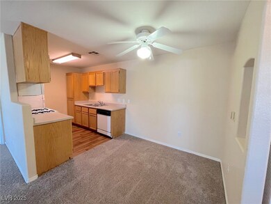 Kitchen with light colored carpet, a ceiling fan,