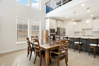 Dining room featuring a towering ceiling, light wood-style flooring, and recessed lighting