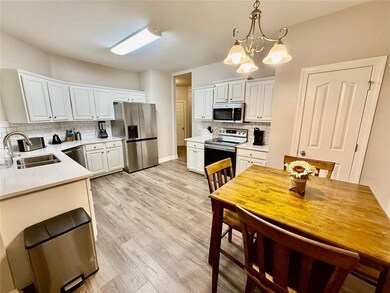 Kitchen featuring appliances with stainless steel finishes, tasteful backsplash, a chandelier, light wood-style floors, and decorative light fixtures