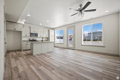 Kitchen with visible vents, baseboards, appliances with stainless steel finishes, light wood-style floors, and a sink