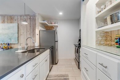 Kitchen featuring open shelves, a sink, white cab