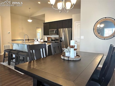 Dining space featuring high vaulted ceiling, visible vents, an inviting chandelier, and dark wood finished floors