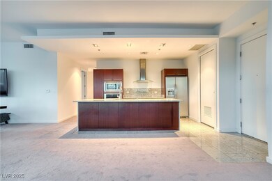 Kitchen with stainless steel appliances, tasteful backsplash, wall chimney exhaust hood, a center island with sink, and light stone counters