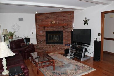Large family room with fireplace.  Sliding doors off den to porch. Beautiful hardwood floors