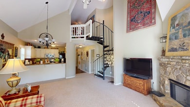 Living area with light carpet, stairway, high vaulted ceiling, and an inviting chandelier