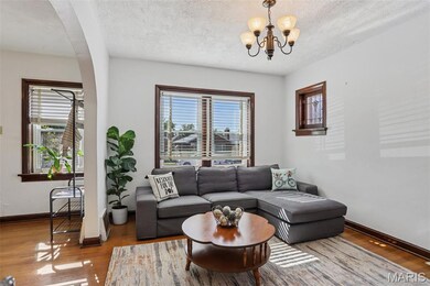 Living area with a textured ceiling, plenty of natural light, wood finished floors, and a chandelier