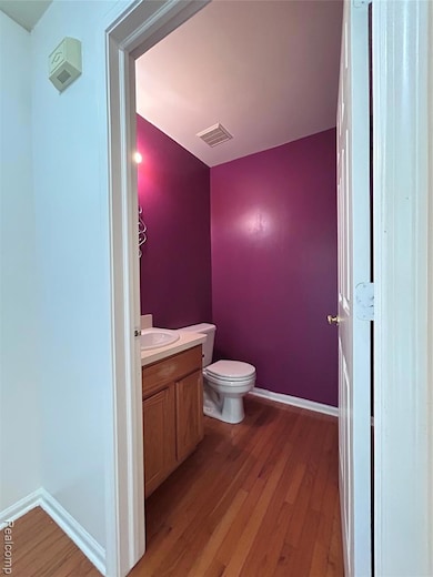 Half bathroom with vanity and dark wood-style floors