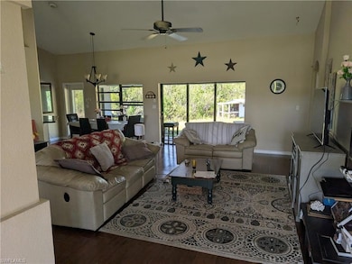 Living area with wood finished floors, ceiling fan, a chandelier, and baseboards