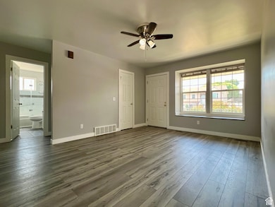 Unfurnished bedroom featuring wood finished floors, a ceiling fan, and ensuite bath