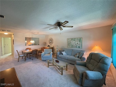 Carpeted living room with a textured ceiling and c